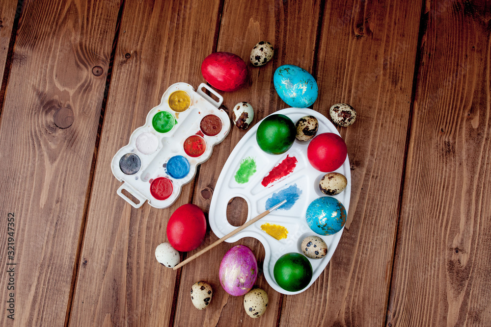 Colored eggs and paint on a wooden table, Easter background Colored eggs and paint on a wooden table, Easter background
