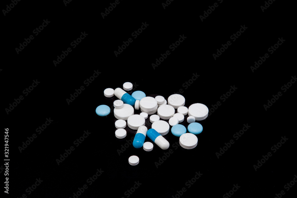 Pills and capsules on a black background. Medicines and dietary supplements