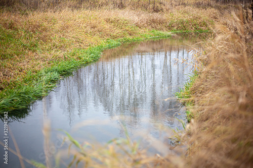 Natural background surface of the river in the field. Natural landscape calm flow of water. Autumn colors. Shallow river.