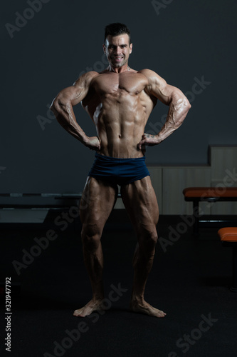 Muscular Man Flexing Muscles In Gym