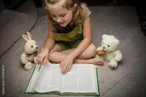 Fotografie Beautiful little girl read book wit favorite toy