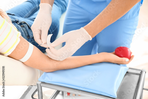Male doctor preparing female donor for blood transfusion in hospital