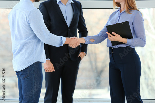 Bank manager and clients shaking hands in office