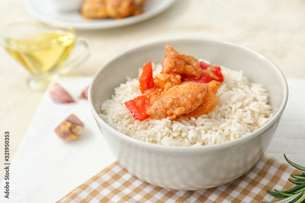 Bowl with tasty rice, chicken and vegetables on white table Bowl with tasty rice, chicken and vegetables on white table