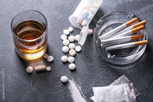 Fotografie Glass of whiskey with cigarettes and drugs on dark background