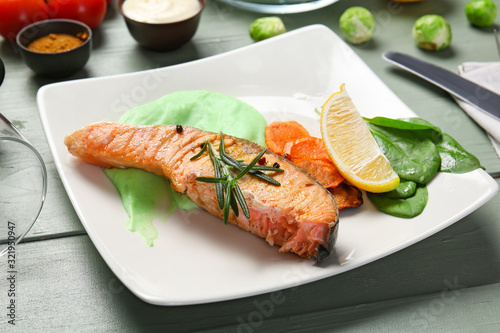 Plate with tasty cooked salmon on table