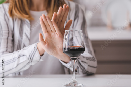 Woman refusing to drink wine at home. Concept of alcoholism photo