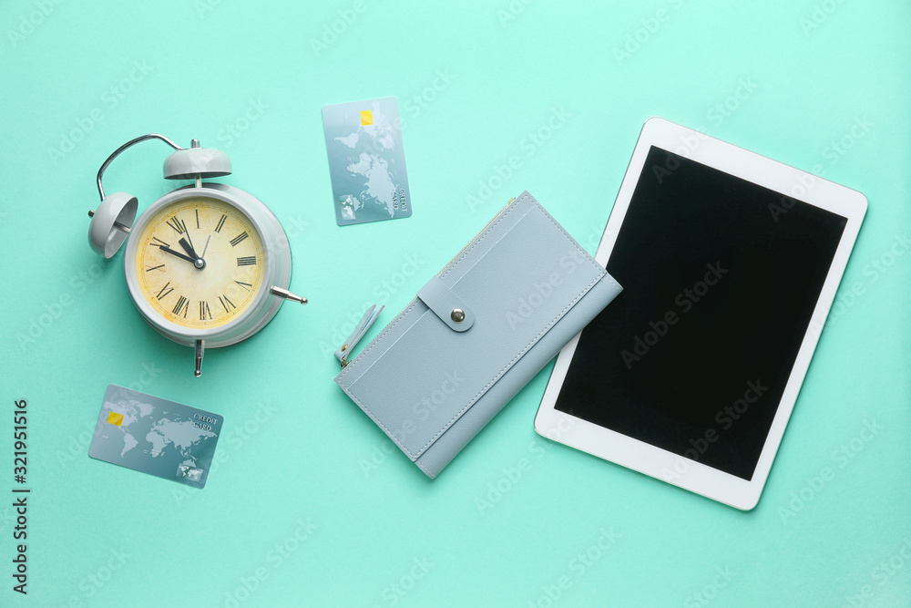 Wallet with tablet computer, credit cards and alarm clock on color background Wallet with tablet computer, credit cards and alarm clock on color background
