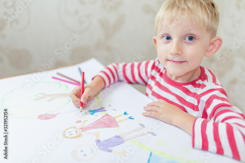 Cute child draws a house and family on paper