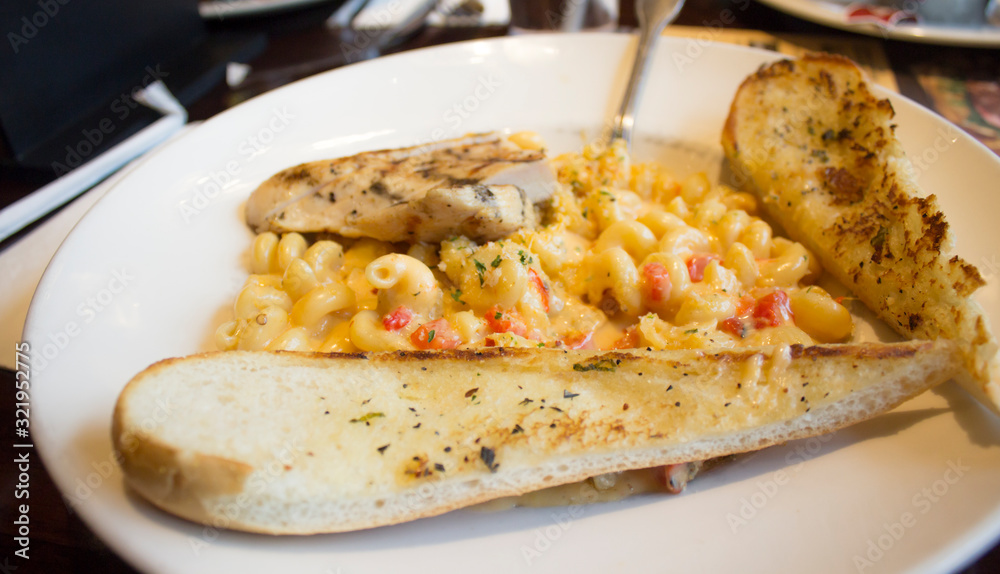 macaroni and cheese with garlic bread on white plate