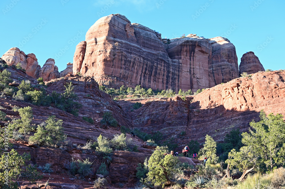 Fototapeta premium Distant hikers on Cathedral Rock Trail near Sedona, Arizona in early morning on clear winter day.