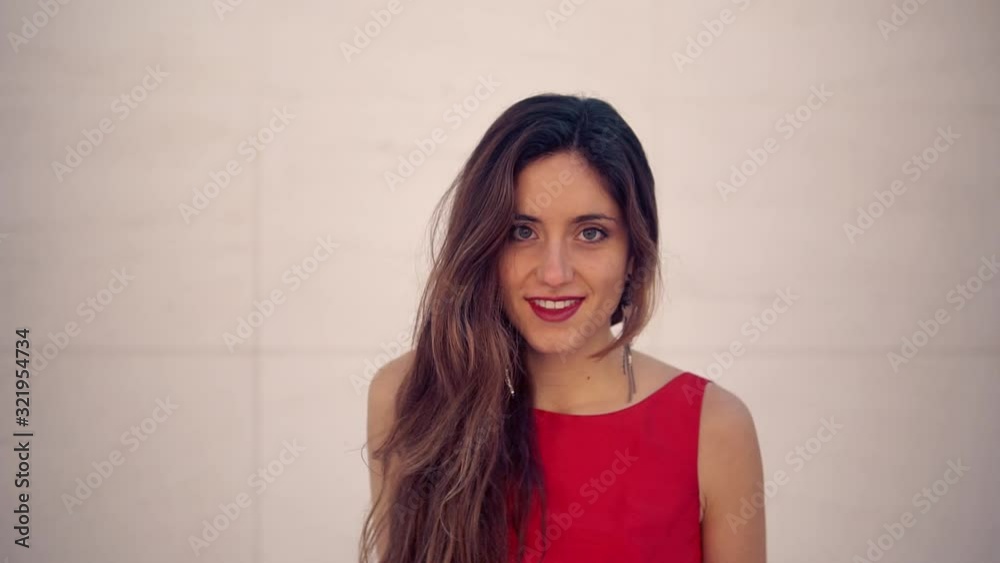 Beautiful woman in red elegant dress walking. Urban white background. She is smiling Beautiful woman in red elegant dress walking. Urban white background. She is smiling