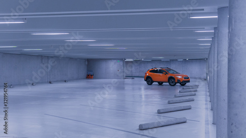 orange car in large white parking garage photo