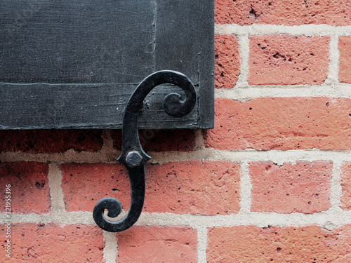 S-shaped black iron shutter holders on a red brick wall of an old house in the urban street of New York neighborhood.