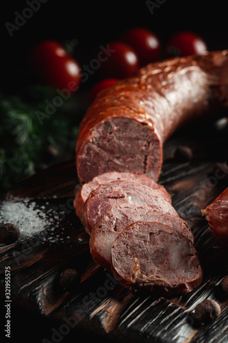Obraz na plátně Ukrainian traditional semi-smoked sausage with herbs and pepper on rustic wooden