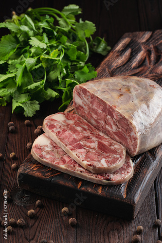 Traditional pork brawn with parsley and pepper on dark wooden board