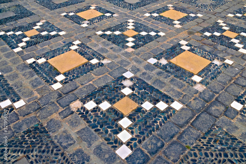 Typical decorative pattern of old Portuguesse and Spanish towns, geometric cross texture laid in various kinds of colorful stones.