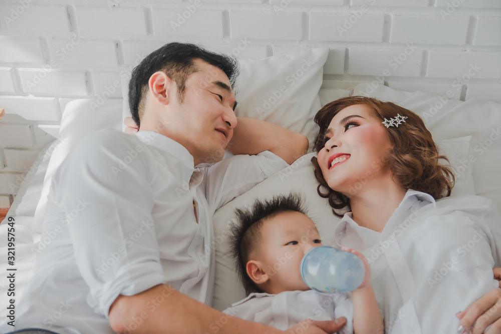 Obraz premium Asian Japanese Family father mother son wearing white shirt posing for photo on white bedroom in white room.To keep memories moment cuteness of son in childhood lifestyle happy