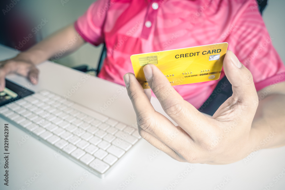Fototapeta premium Man paying with credit cards on computer at home.