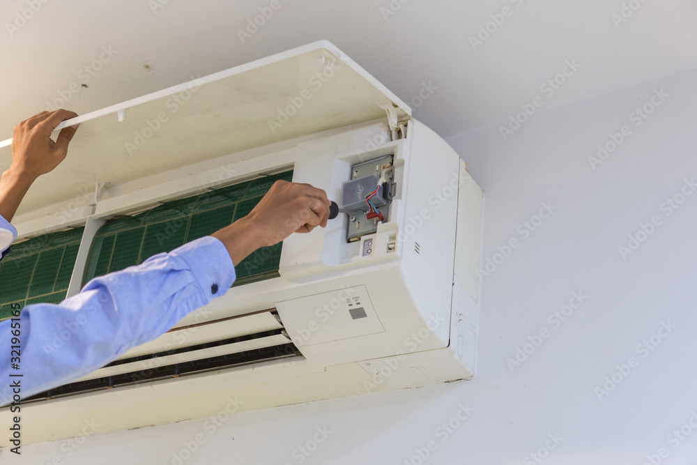 Technician repairing air conditioner on the wall .