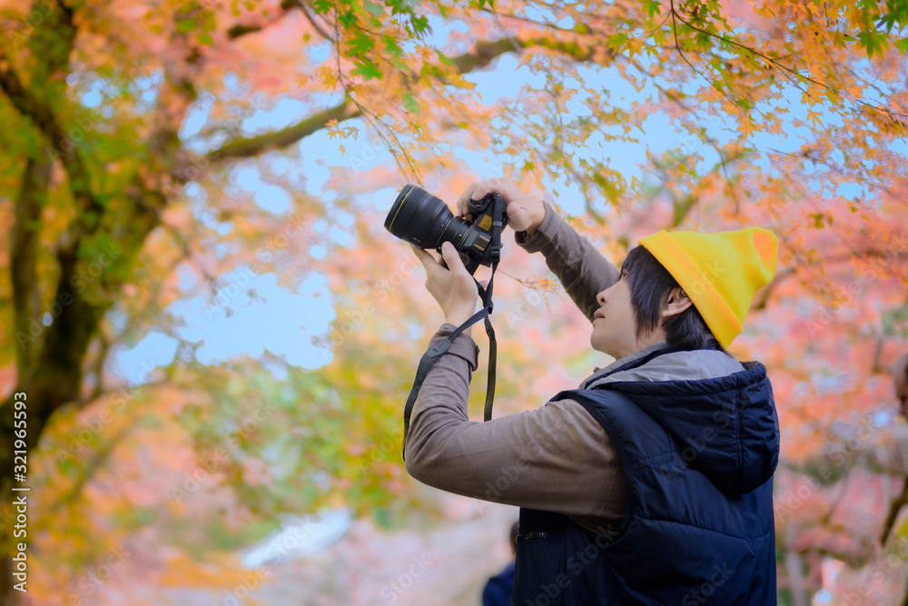 photographer holding camera gear takes picture of the nature autumn season change in Japan
