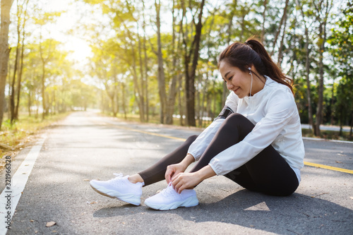 Closeup image of a woman runner tying shoelaces and getting ready for run in city park