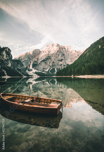 Natural landscapes of the lake Braies (Lago di Braies) with boat and reflection of the mountain peak in Dolomites, Italy
