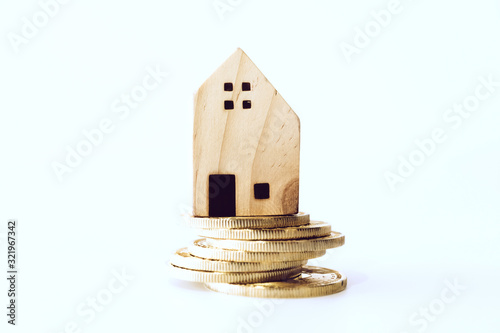 Mini house model on gold coin with clean white copyspace background. Business invest property saving.