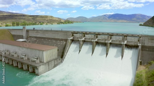 Drone footage of Lake Aviemore Hydo Dam in The South Island of New Zealand while spilling water. Rising up from the Waitaki river with spectacular views of the lake on a sunny blue sky day. photo