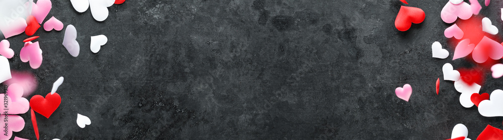 Fototapeta premium Soft red, pink, and white cloth hearts falling on dark background.