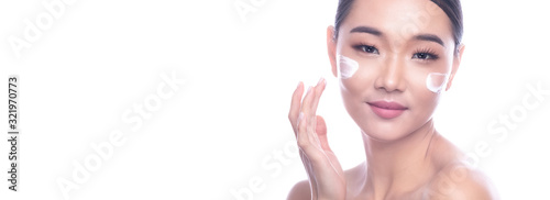 Beautiful Young Asian Woman with Clean Fresh Skin isolate on white background. Spa, Face care, Facial treatment, Beauty and Cosmetics concept. Cream on face, right hand on face, smile. Banner frame.