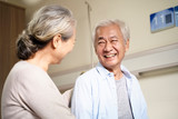 happy asian old couple chatting in hospital ward