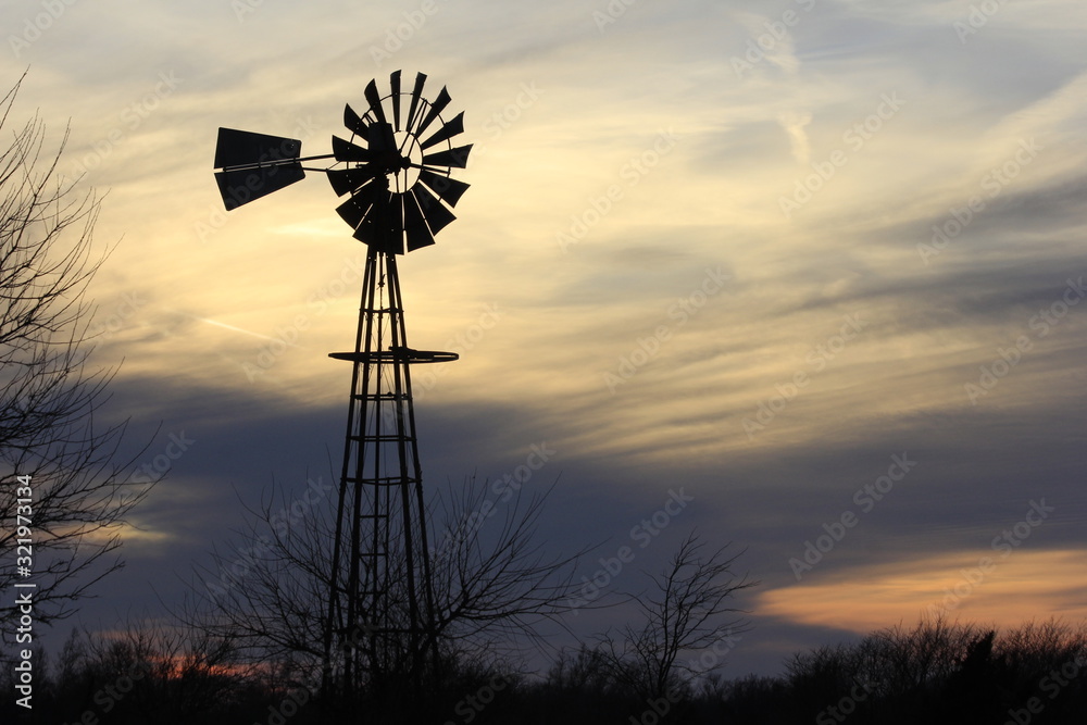 Kansas Windmill at Sunset with a colorful sky out in the country north of Hutchinson Kansas USA. Kansas Windmill at Sunset with a colorful sky out in the country north of Hutchinson Kansas USA.