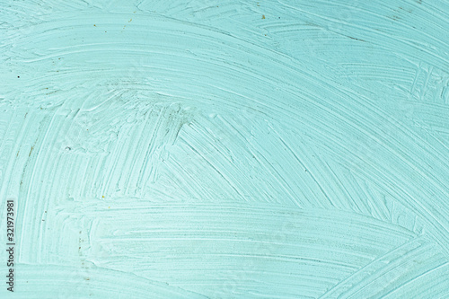 A close-up texture background of a distressed relief light aqua turquoise wall painted with wide strokes