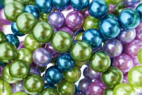 colored pearls close-up. pearl beads round background.blue, purple, green and pink beads .Beautiful decoration background in cold colors.