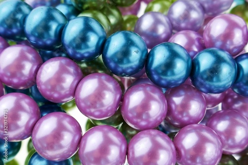 colored pearls close-up. pearl beads round background.blue, purple, green and pink beads texture.Beautiful decoration background in cold colors.