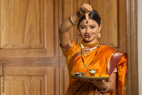 Maharashtrian woman in traditional dress applying tilak holding a pooja plate. photo