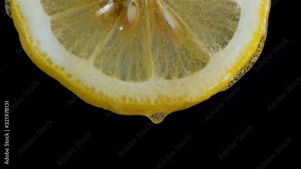 Honey pouring on half slice cut of fresh lemon against black background
