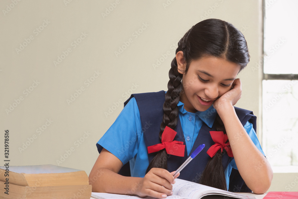 Rural girl in school uniform sitting at table reading book Rural girl in school uniform sitting at table reading book