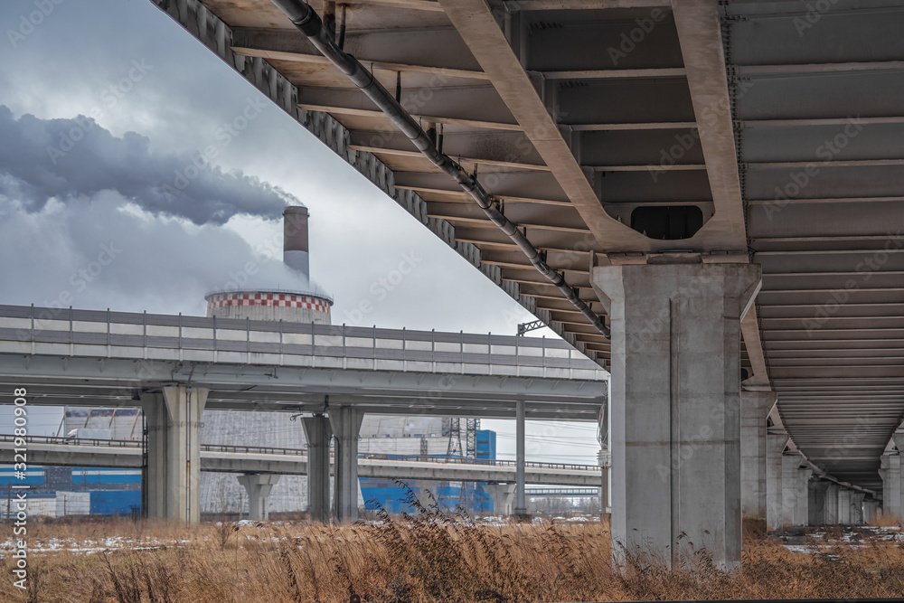 Concrete pillars of the viaduct and the Smoking chimneys of large enterprises. The concept of urbanization. Concrete pillars of the viaduct and the Smoking chimneys of large enterprises. The concept of urbanization.