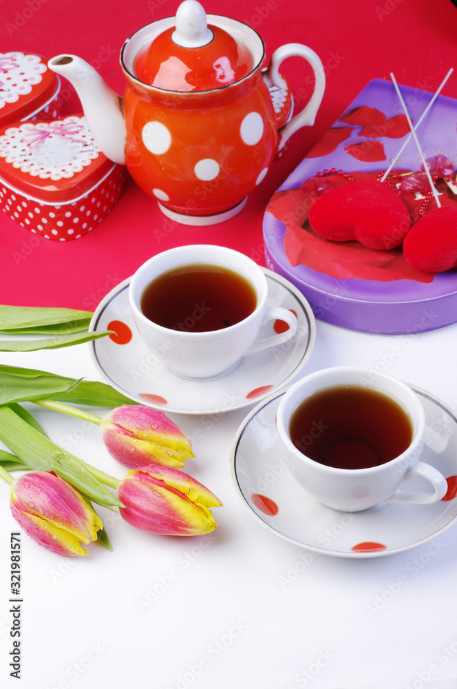 Fototapeta premium Tea for two. Two cups of tea, a bouquet of tulips, a porcelain teapot, gifts on a table with a white tablecloth.
