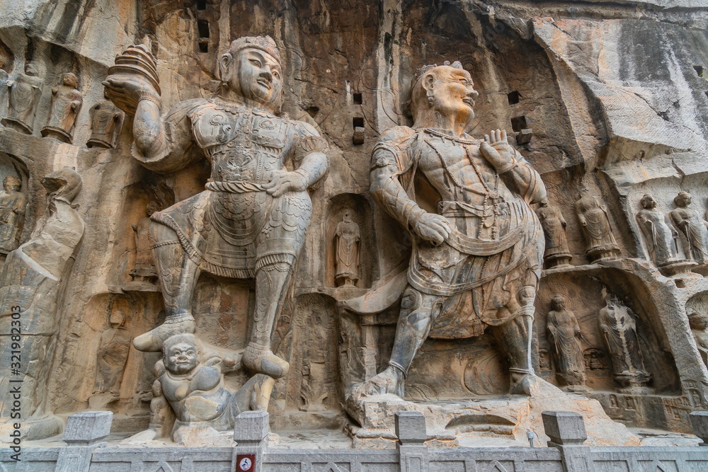 Figure of a mighty guardian  and Vajrapani with a thunderbolt holder in Fengxian temple. Longmen Caves in Luoyang, Henan province, China