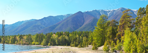 Lake Baikal in June. View of the mountains of the Holy Nose Peninsula from the sandy shore of the Barguzinsky Bay. Summer travels on the lake. Beautiful landscape, panorama photo