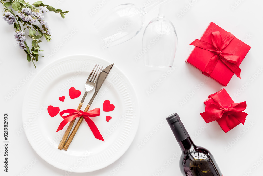 Romantic dinner on Valentines Day. Wine, plate, present box on white background top-down Romantic dinner on Valentines Day. Wine, plate, present box on white background top-down