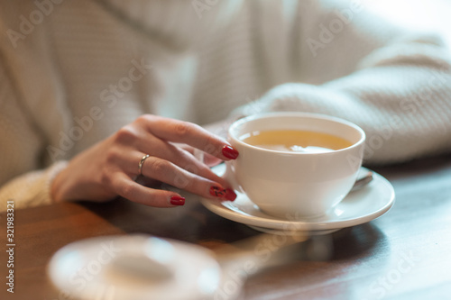 Woman holds white cup with tea