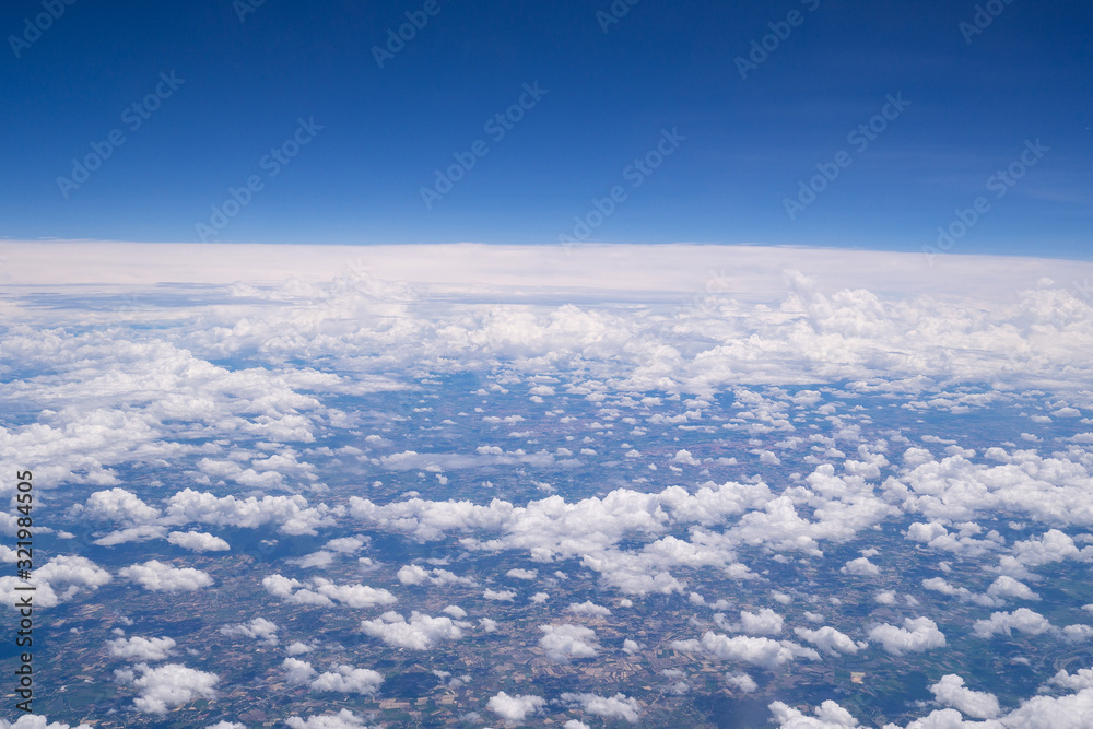 Beautiful view from airplane window above the clouds. Bright blue sky and white clouds. Skyline background with copy space.