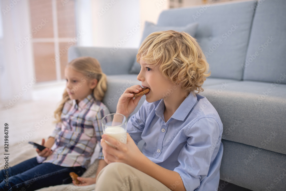 Boy eating biscuit and drinking milk, girl holding remote control Boy eating biscuit and drinking milk, girl holding remote control