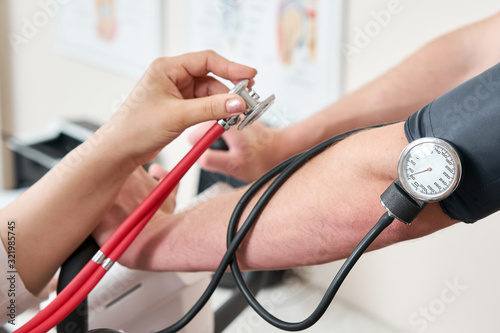 The nurse measures arterial tension. Man patient, pedaling on a bicycle ergometer stress test system for the function of heart checked. Athlete does a cardiac stress test in a medical study photo