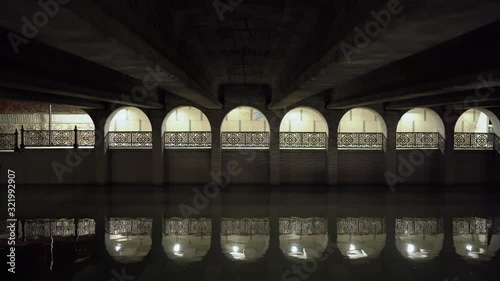 Pedestrian passage under the bridge on Salgir river embankment in Simferopol at night. Empty paved footpath lit by lanterns in autumn. photo