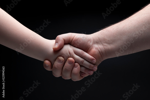 Handshake, father holds hand son. Father and Son Relationship Concept. Dark background